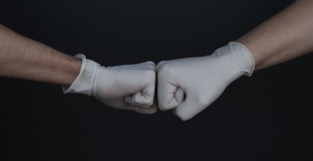 Hands with plastic gloves fist bumping